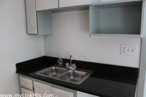 sink and black granite with cabinet and storage for a coffee bar