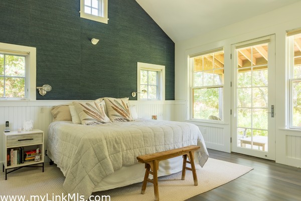 Primary bedroom with doors out to a private deck overlooking the pond