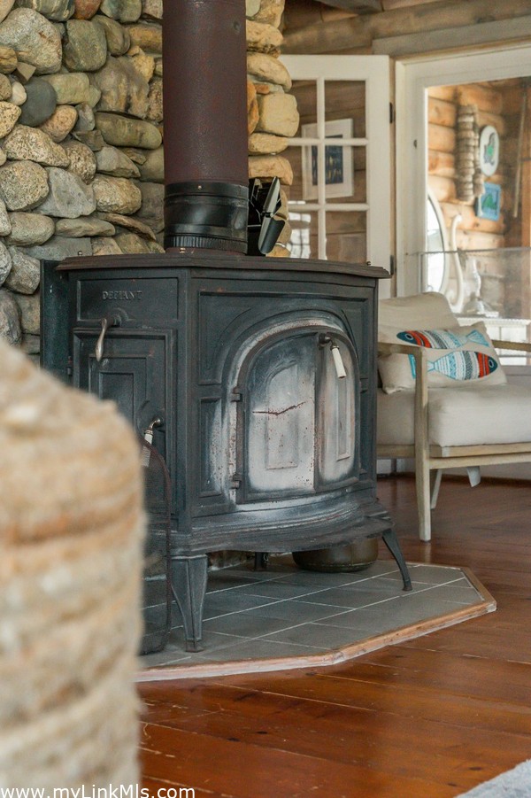 Wood stove accents the beach stone fireplace and provides warmth on chilly evenings