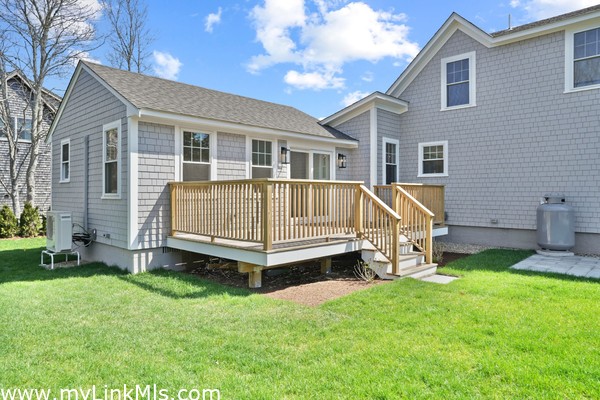 Spacious outdoor living atop the first floor deck off the accessory dwelling unit. Adjacent patio and lush green yard.