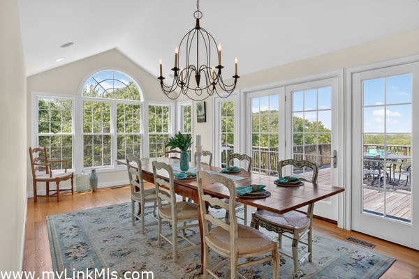 The dramatic arched windows and a classic statement chandelier, this bright and airy room offers panoramic views of the surrounding landscape and opens directly onto the expansive back deck, creating a flawless indoor-outdoor flow for entertaining