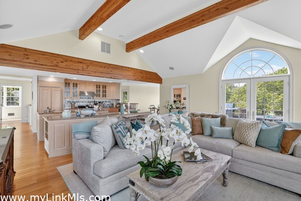 Spacious and airy living room showcasing gorgeous post-and-beam details, a central fireplace, and beautiful hardwood floors