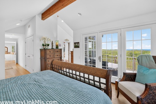 Primary bedroom featuring vaulted ceilings, exposed beams, and private deck access