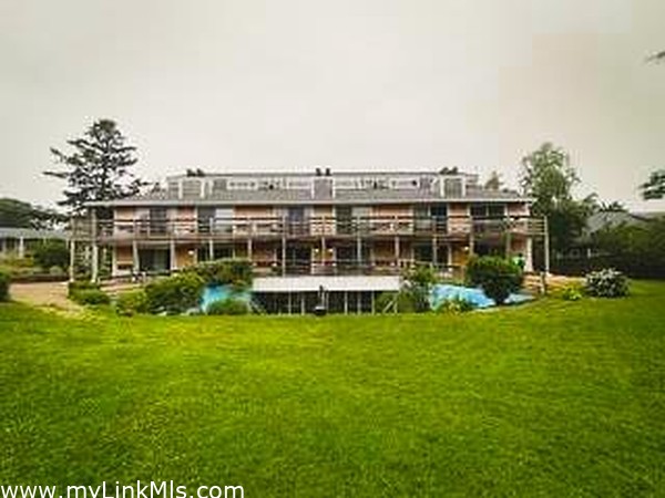 exterior of condo building looking over large grassy yard